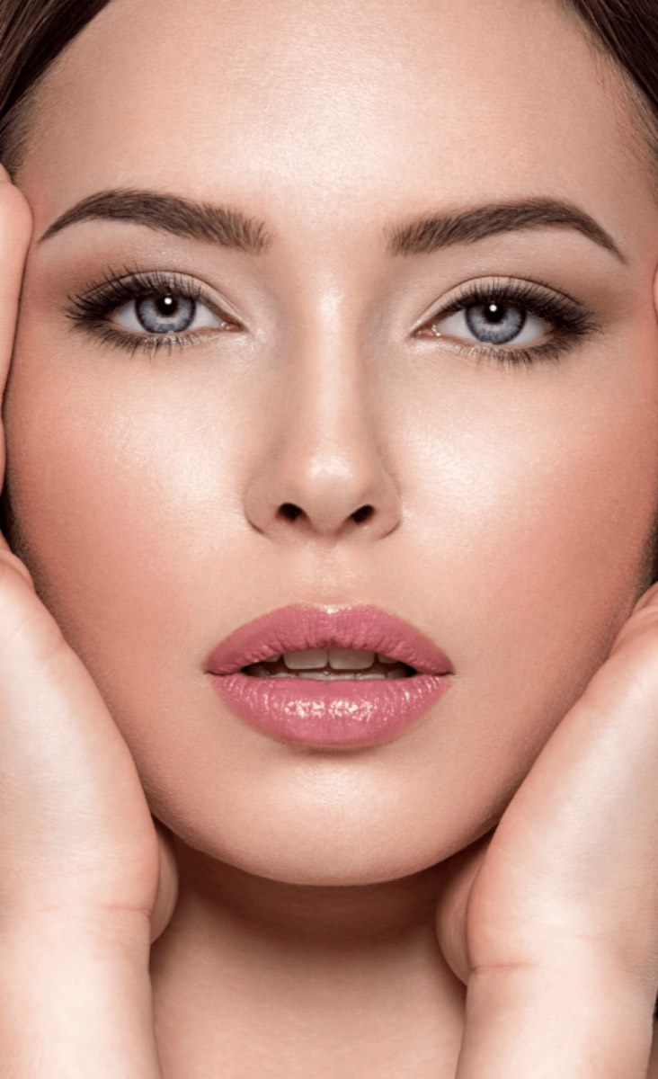 Woman with a defined chin and jawline framing her face with her hands