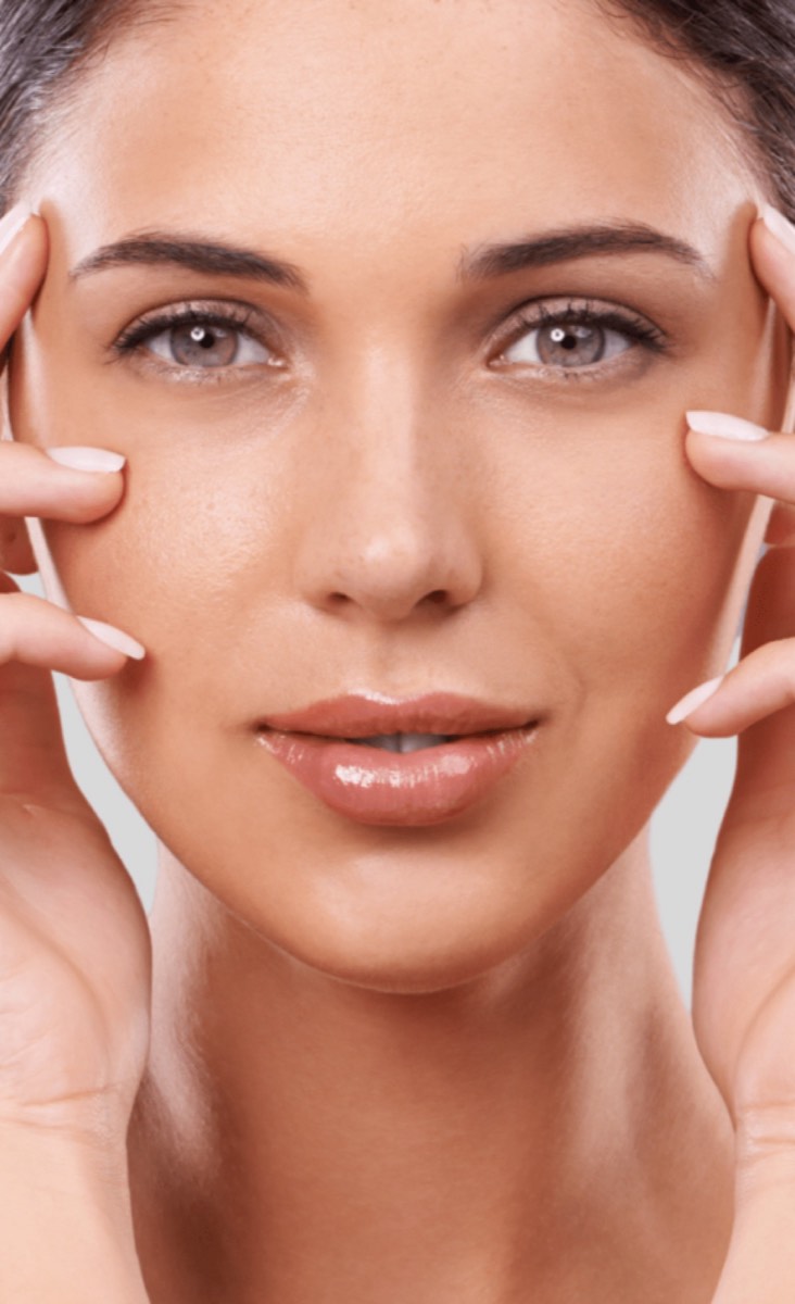 Woman with smooth, even skin resting her fingertips at her temples