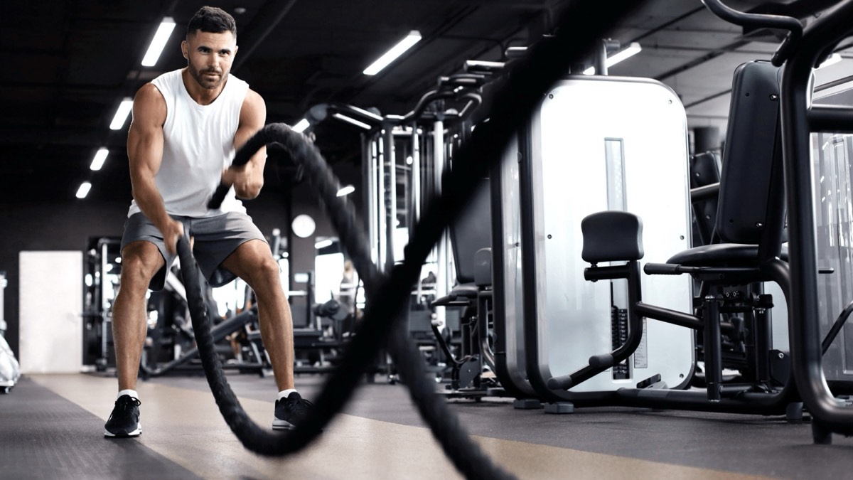 Athletic man training with battle ropes in a gym