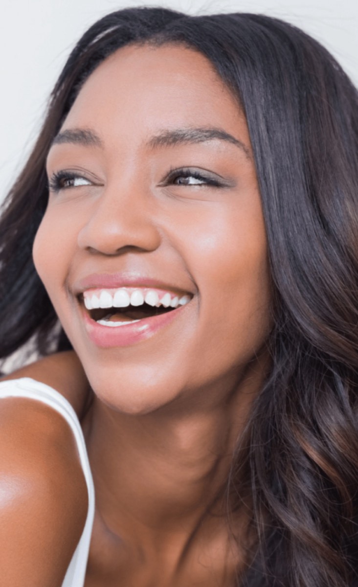 Smiling woman with clear, glowing skin looking over her shoulder