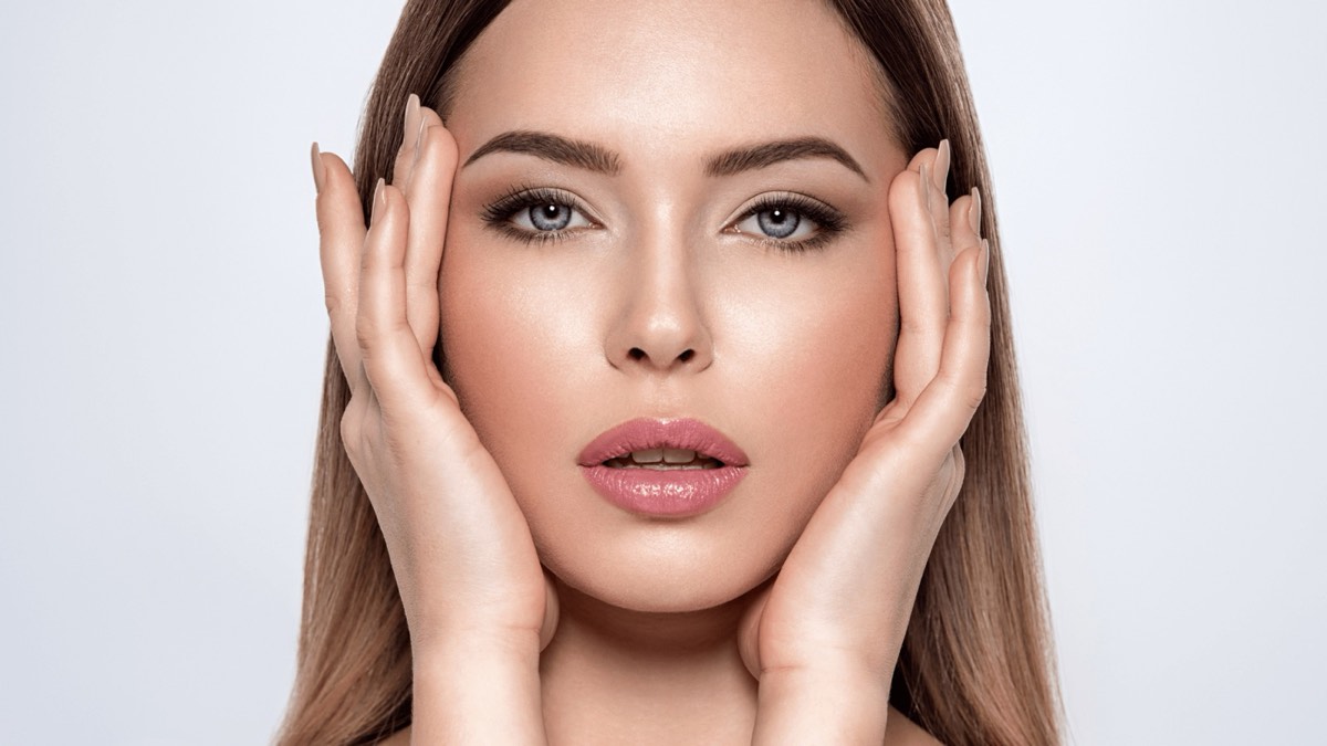 Studio portrait of a woman framing her face with both hands