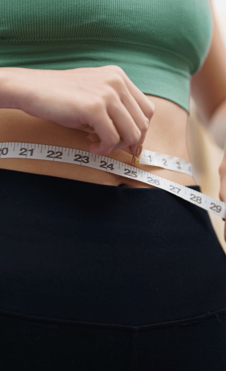 Woman measuring her waist with a tape measure